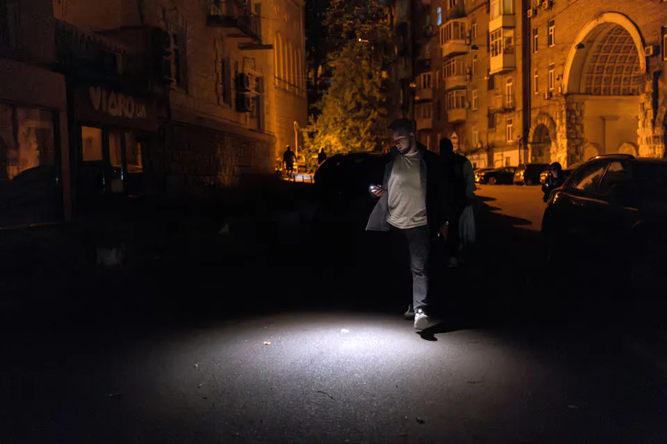 Чоловік використовує свій телефонний ліхтар, коли йде темною вулицею під час часткового відключення електроенергії, на тлі нападу Росії на Україну, Київ, Україна, 16 травня 2024 ркоу